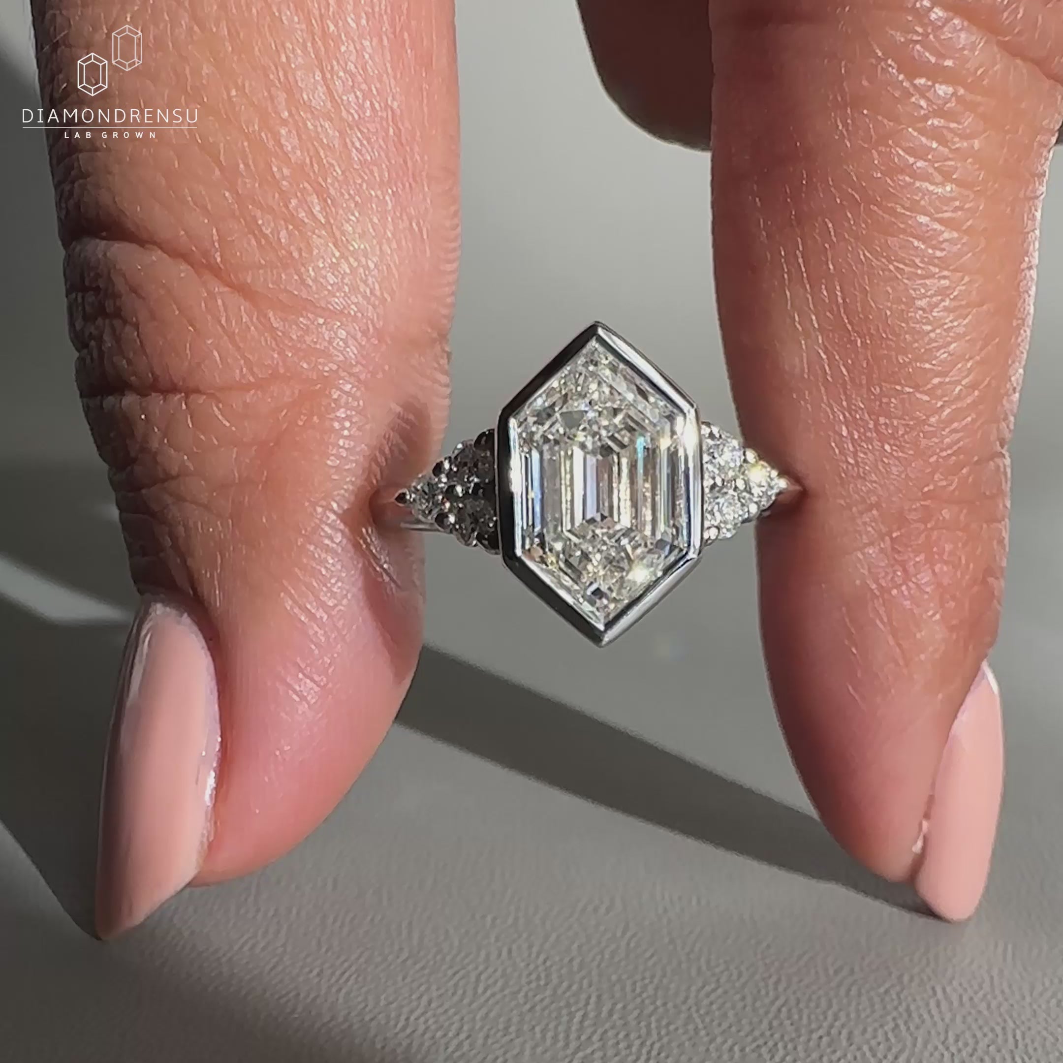 Hexagon diamond engagement ring with round side stones.
