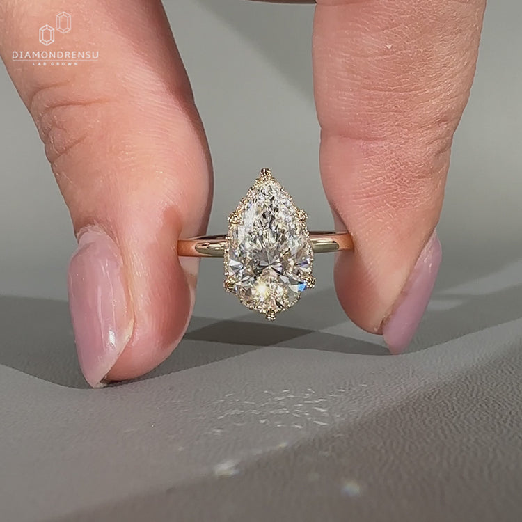 Pear diamond engagement ring with round cut halo setting.