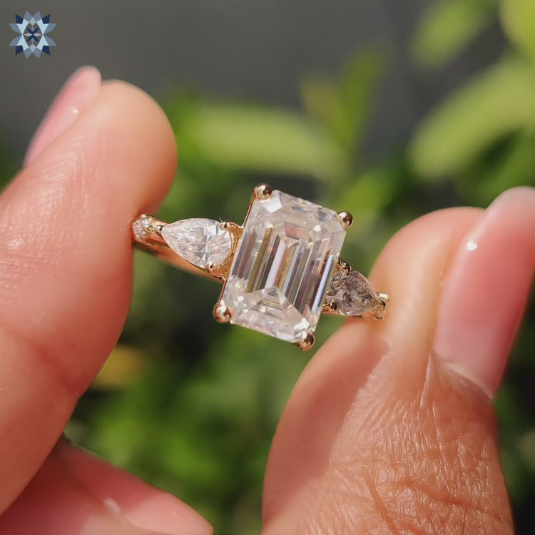 Five stone moissanite engagement ring featuring emerald centre and pear accents.
