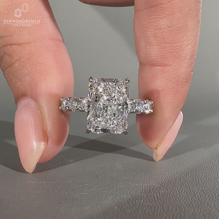 Radiant diamond ring with round cut u shape pave setting.