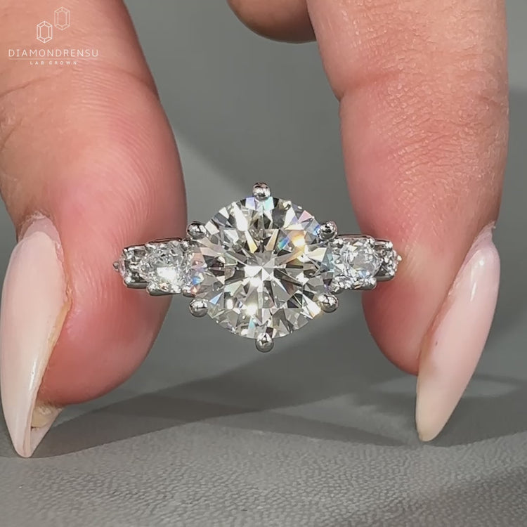 Round diamond ring with pear side stones.
