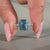 Cushion cut blue diamond ring with four claw prongs.
