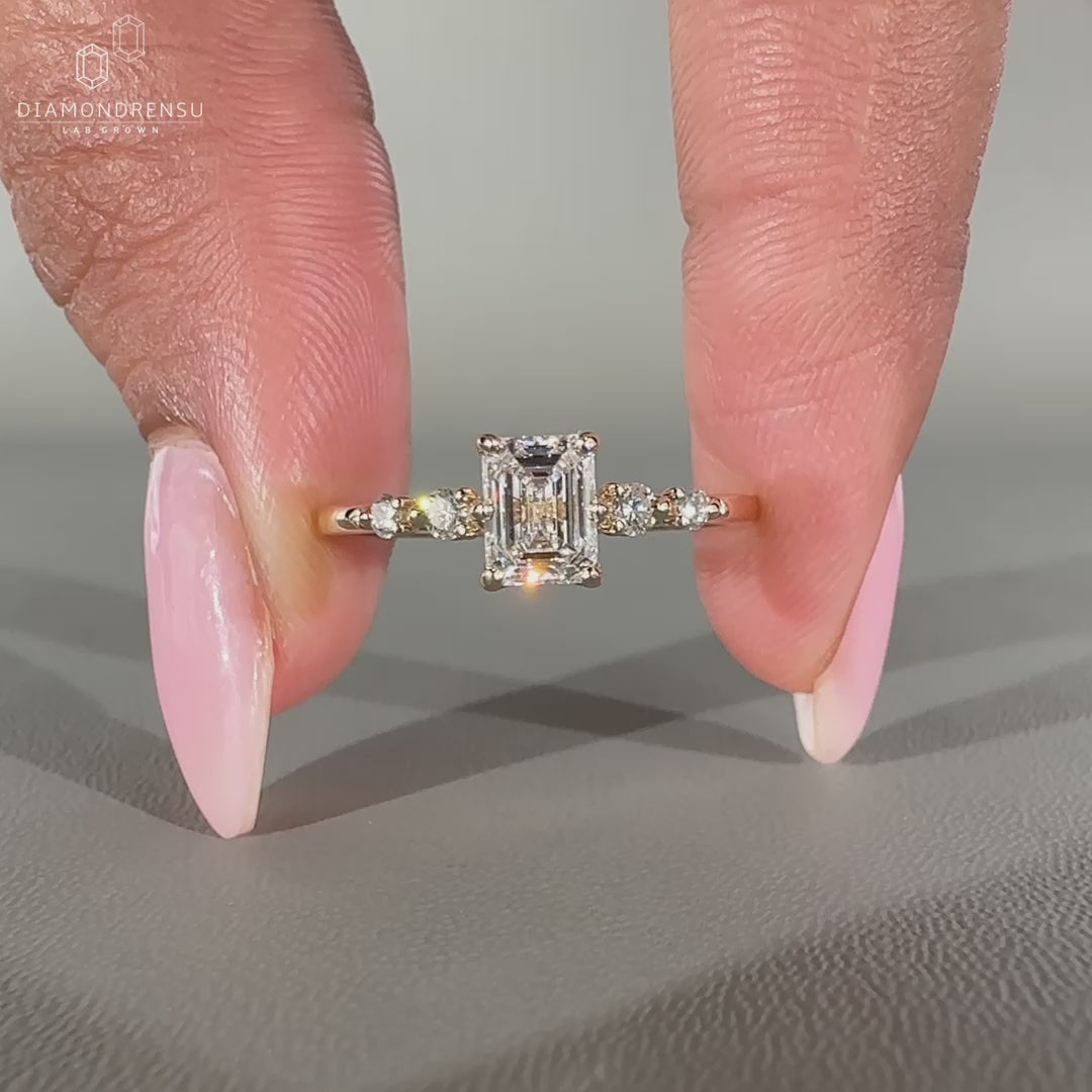 Five stone ring featuring emerald cut center diamond.
