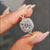 Moissanite halo ring featuring round cut centre and prong setting.
