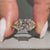 Princess cut ring with twisted shank and leaf motifs.