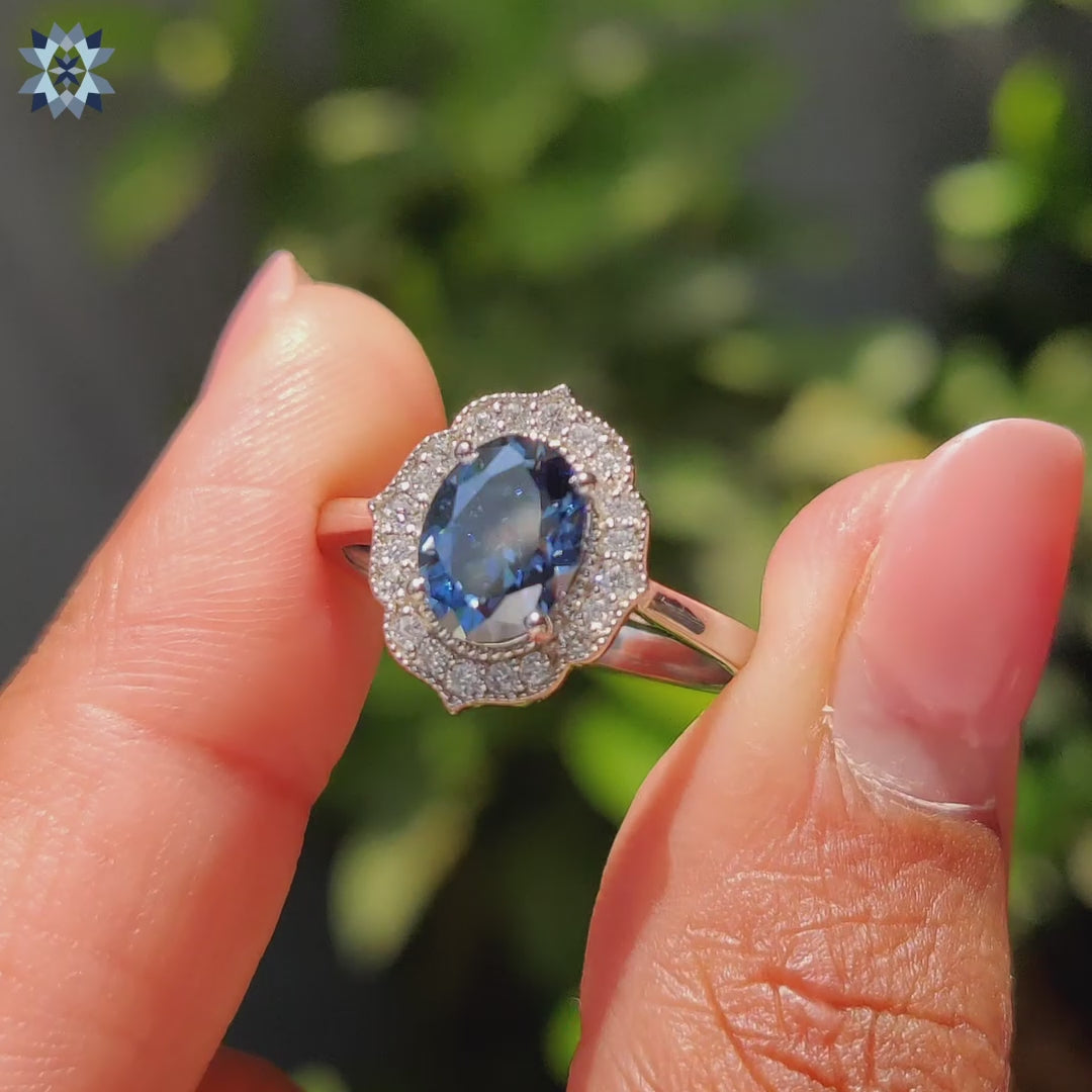 Royal dark blue Moissanite ring in oval cut with white gold halo and milgrain detailing.
