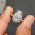 Halo engagement ring featuring moissanite pear cut and handmade band.
