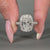 Halo diamond ring featuring three side pave engagement band design.
