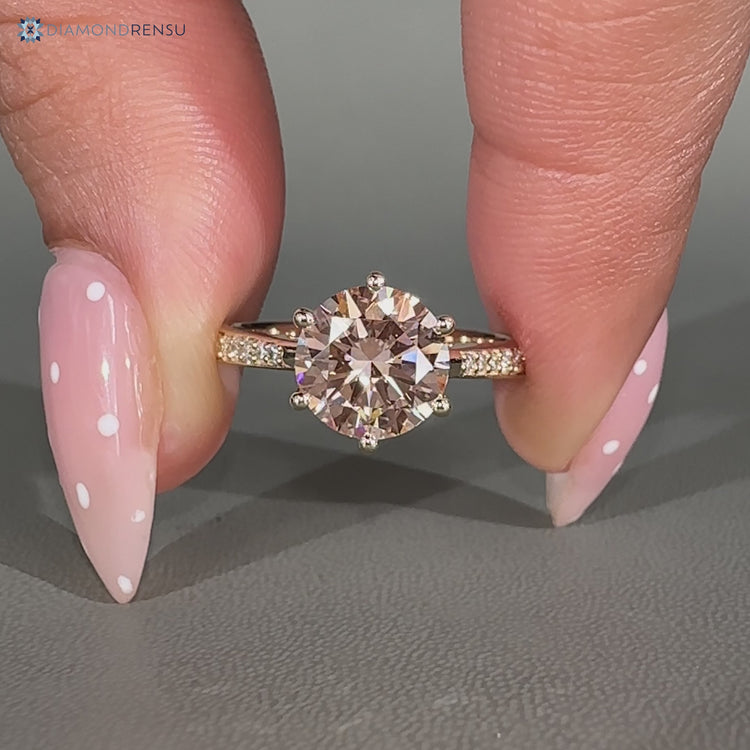Pink centre diamond engagement ring with round side stones.