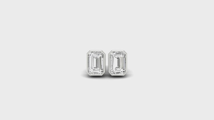 White gold bezel set earrings with emerald step cut diamonds.
