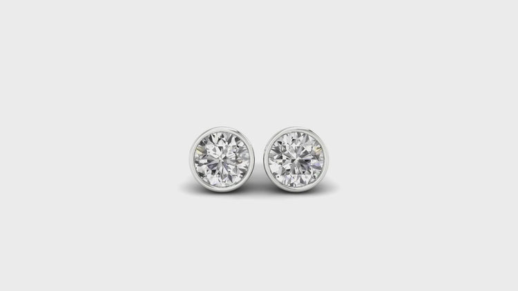 Round cut diamond earrings in white gold bezel setting.
