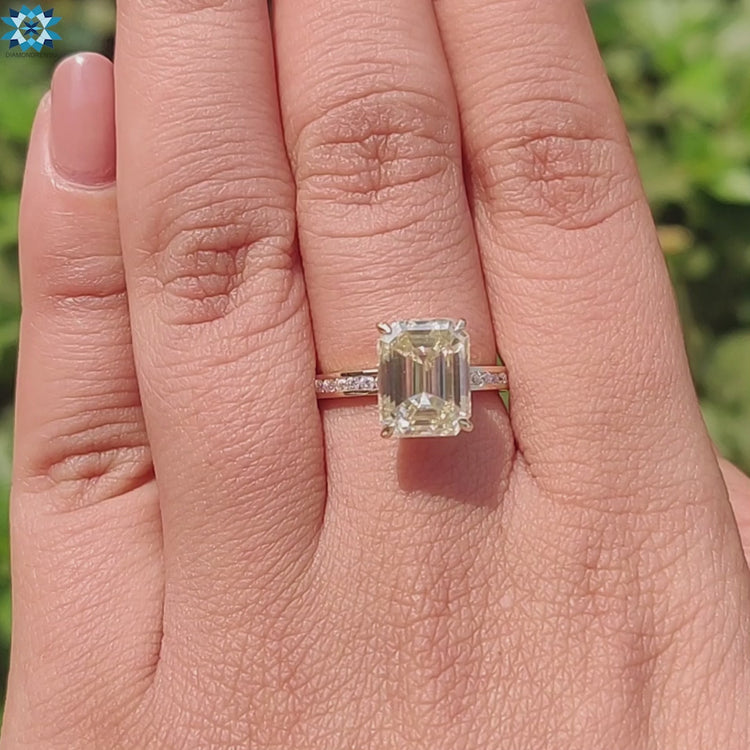 Emerald cut moissanite ring featuring hidden halo and yellow gold band.
