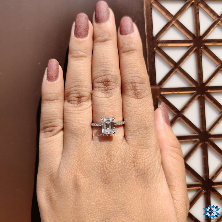Handmade white gold ring with emerald cut moissanite and side accents.
