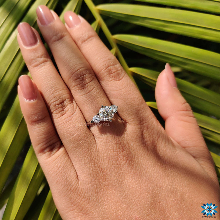 White gold ring with three round moissanite stones in prong setting.
