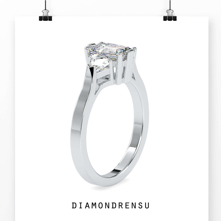 Trillion side stone ring with emerald cut centre in white gold.
