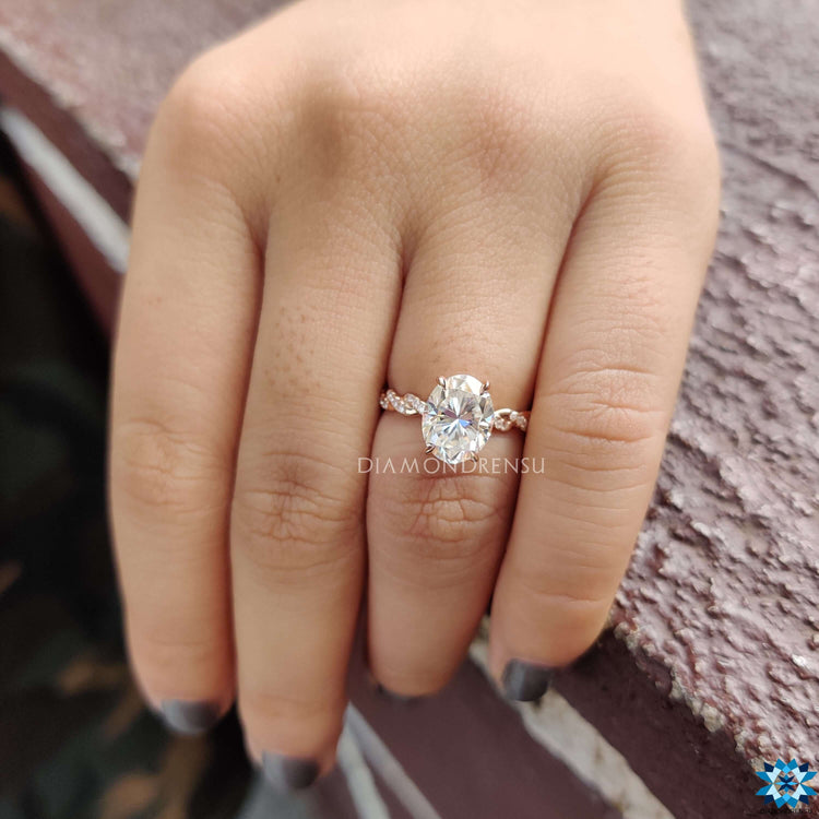 Rose gold ring with oval cut moissanite in a prong setting.
