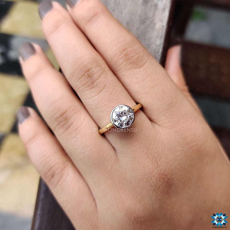 Modern bezel moissanite ring crafted in yellow gold.
