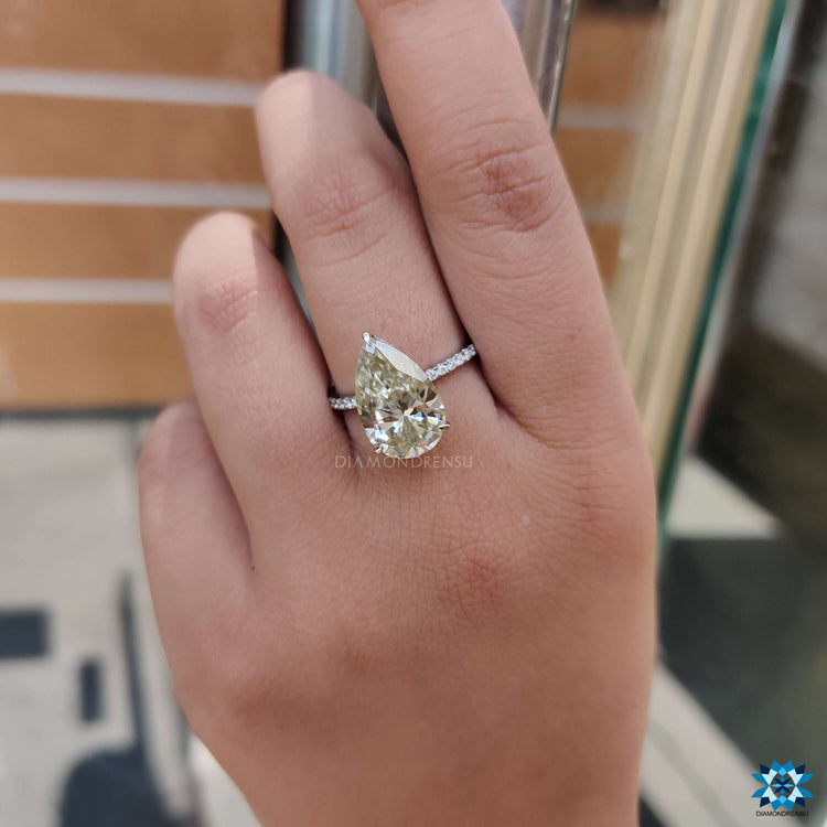 Elegant three-prong setting holding a light yellow pear shaped stone.
