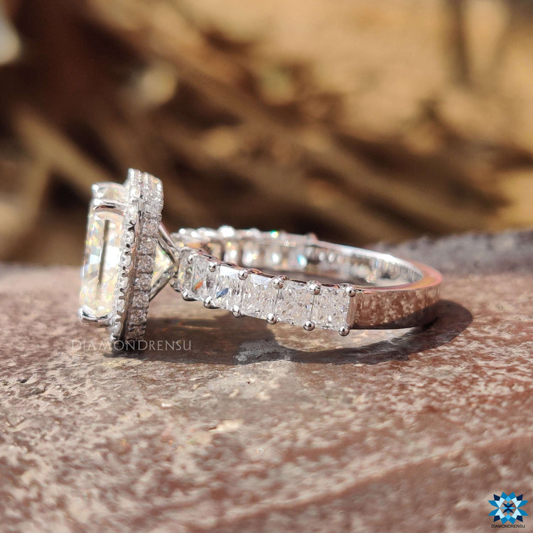 Radiant cut moissanite halo ring with white gold band and pave accents.
