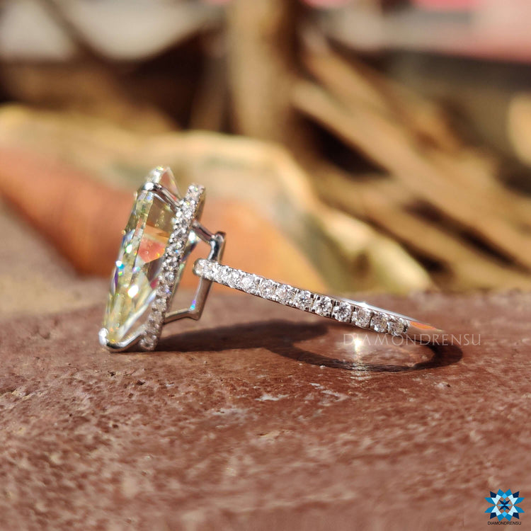 White gold engagement ring featuring a light yellow pear center stone.
