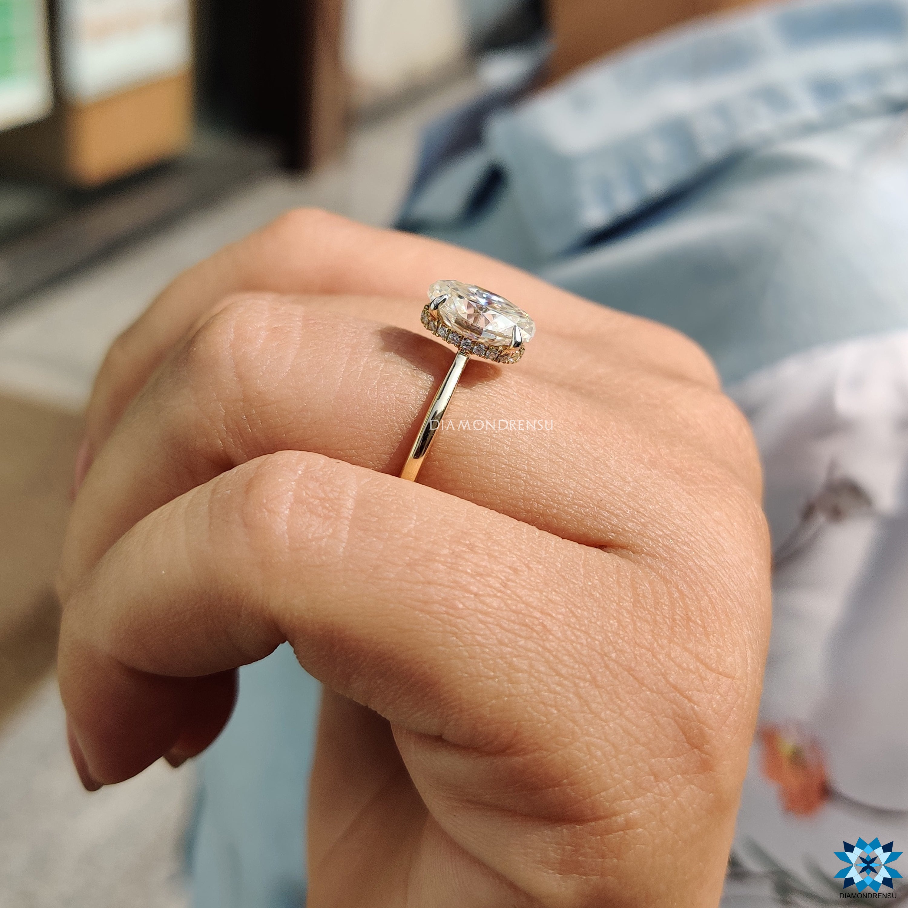 4 claw prong setting securing oval cut moissanite in halo design.
