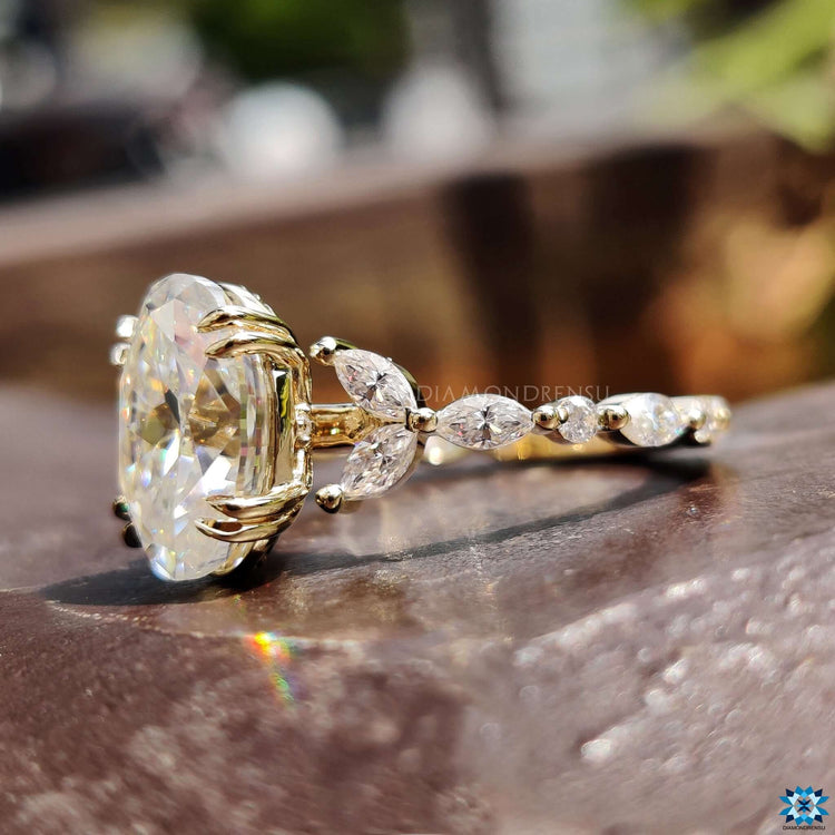 Oval cut moissanite engagement ring with side marquise and round diamonds.
