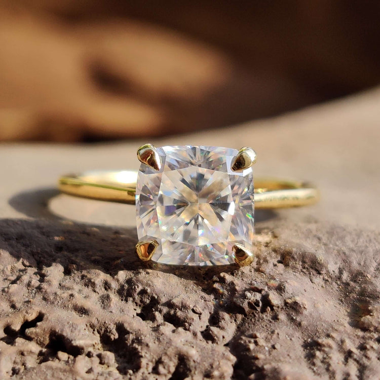 Cushion cut moissanite solitaire ring in yellow gold.
