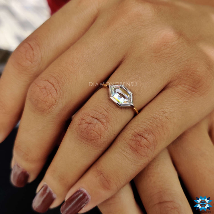 Two-tone white and yellow gold engagement ring with bezel set moissanite.
