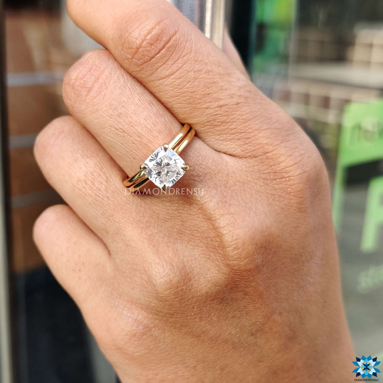 Prong set cushion moissanite ring in gold band.
