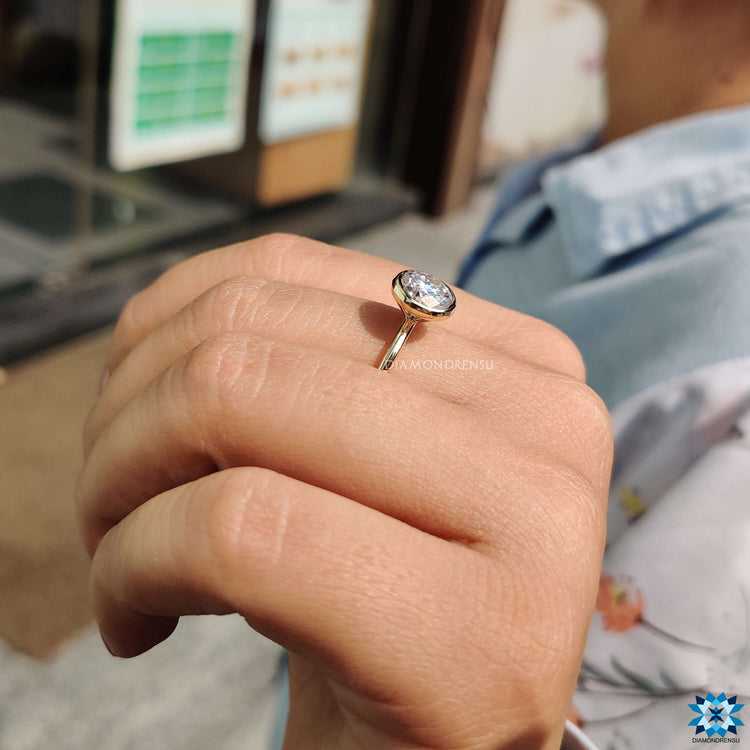 Smooth bezel set moissanite ring in warm yellow gold.
