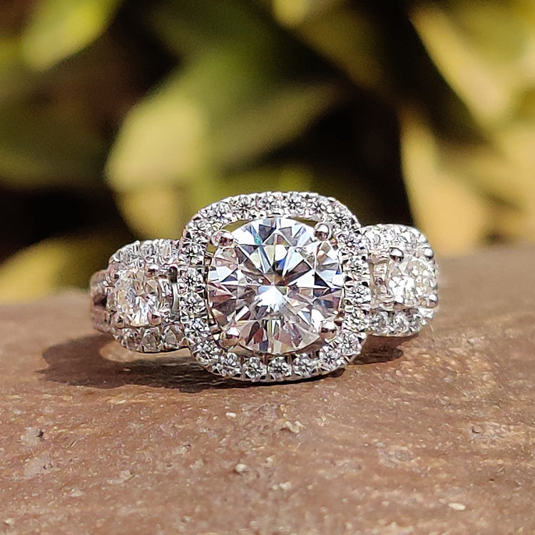 Three stone halo engagement ring with round cut moissanite.
