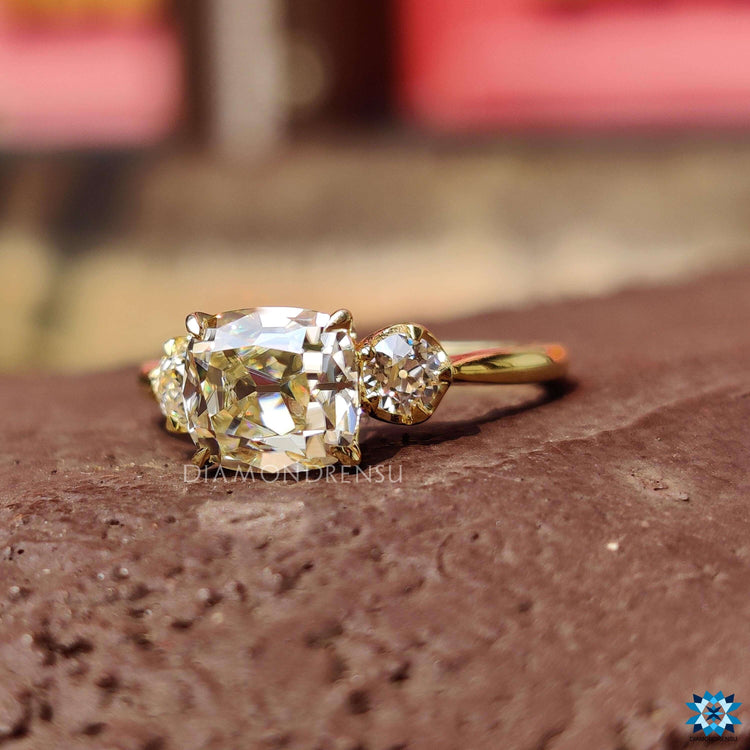 Yellow gold ring crafted with round old European cut side stones and a cushion cut center.
