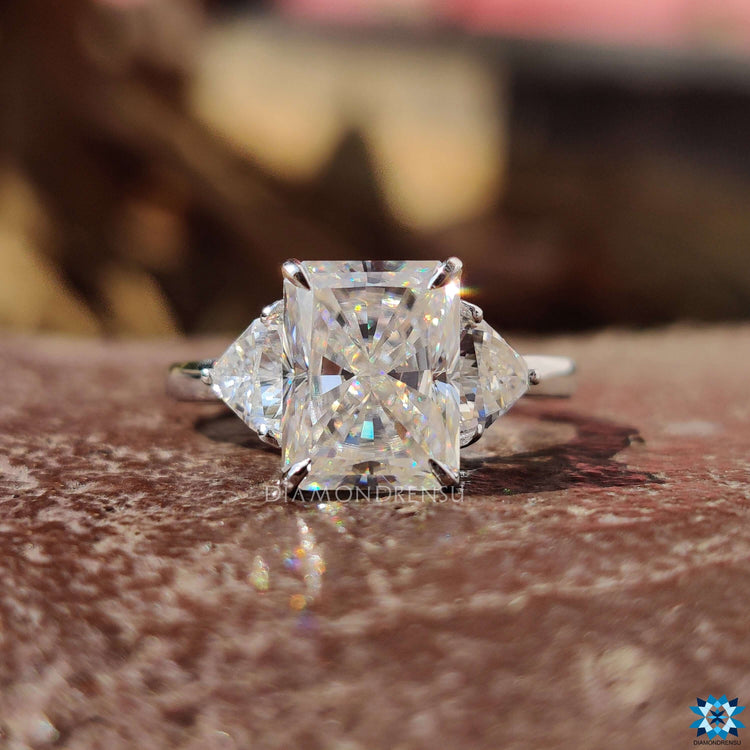 Radiant moissanite engagement ring with trillion cut accents.

