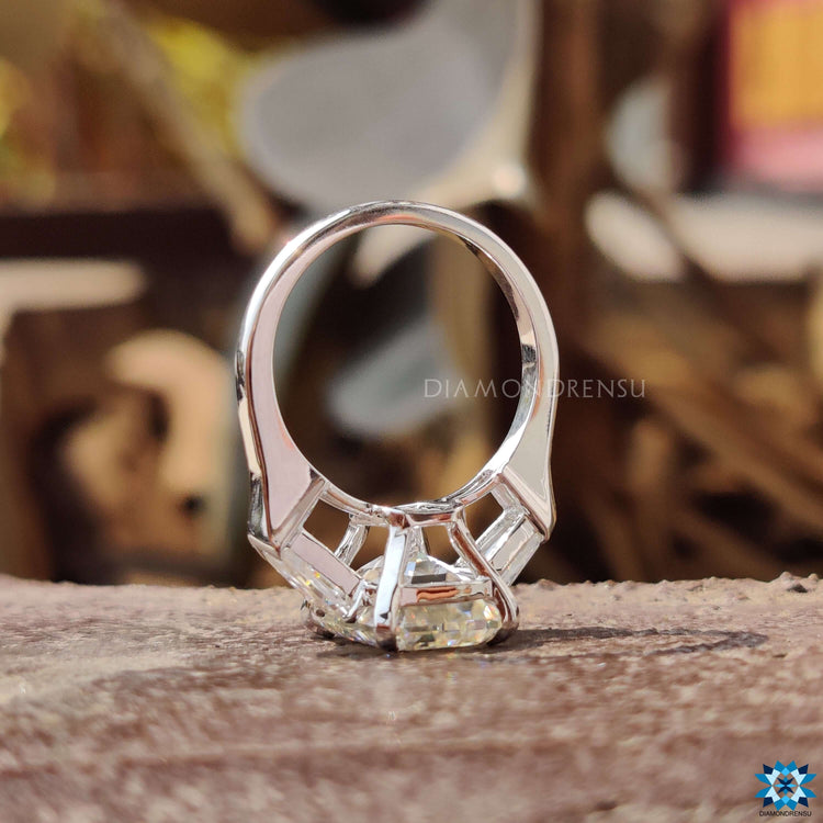 Prong set emerald cut moissanite ring with bullet shaped accents.
