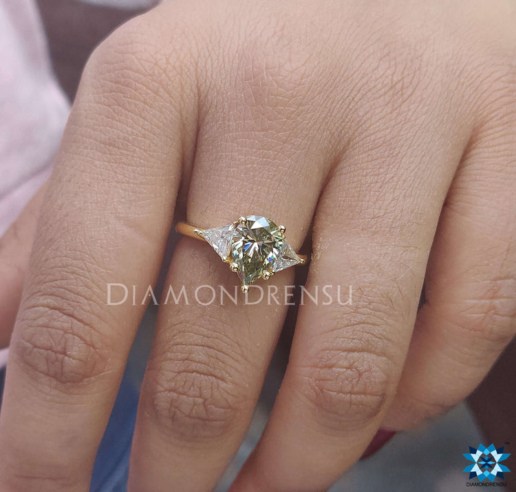 Pear and triangle moissanite ring set in a yellow gold band.