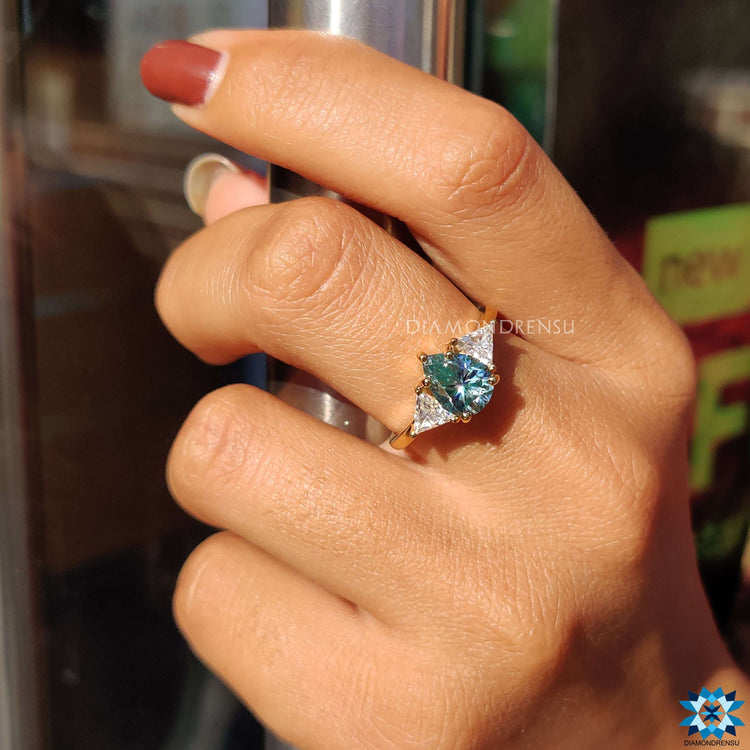 Yellow gold ring with cyan blue pear and triangle cut stones.
