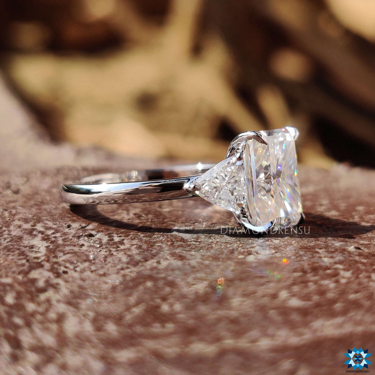 Three stone moissanite ring in cathedral setting with claw prongs.
