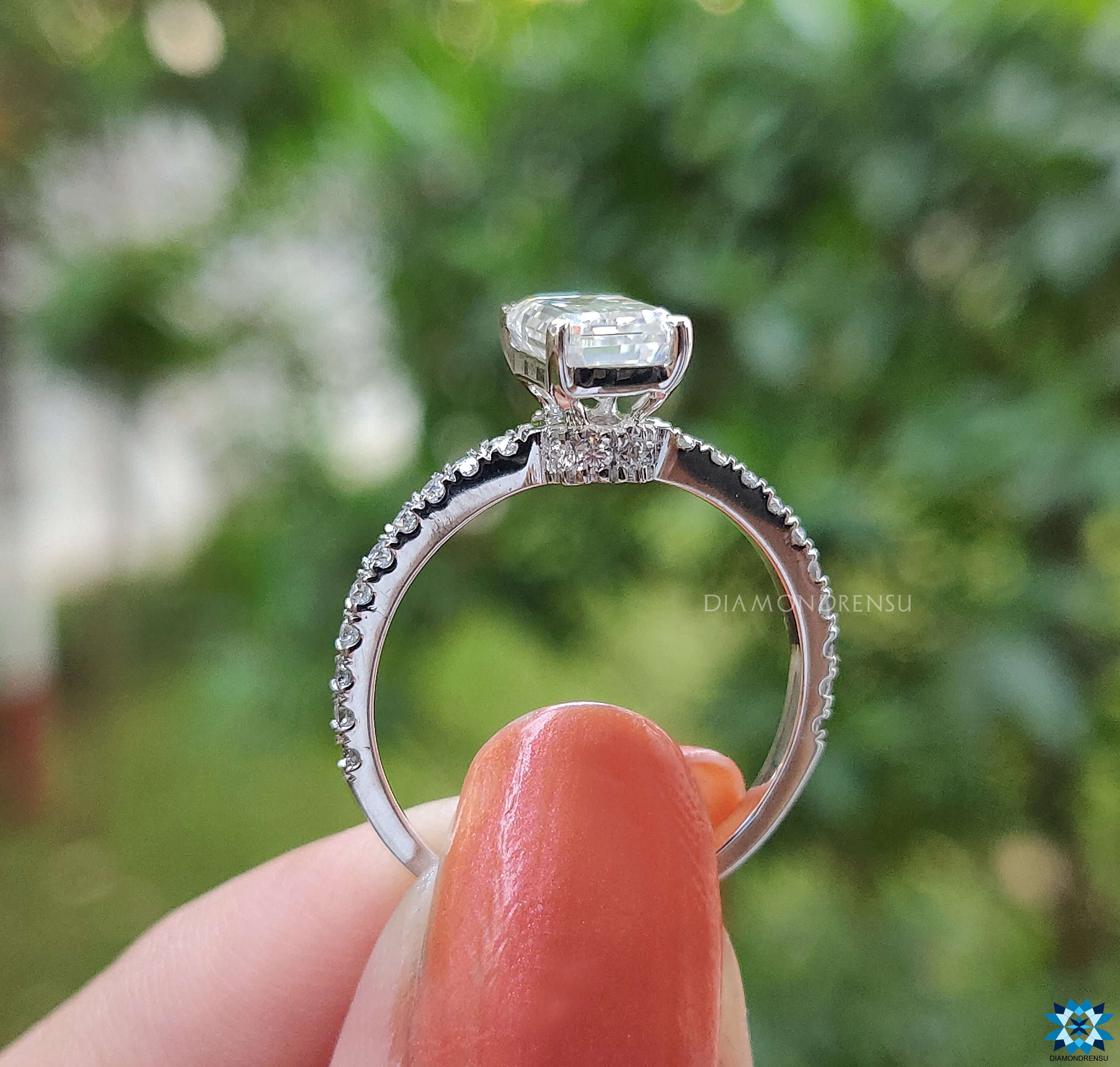 Prong setting ring with emerald cut moissanite centre and pave accents.