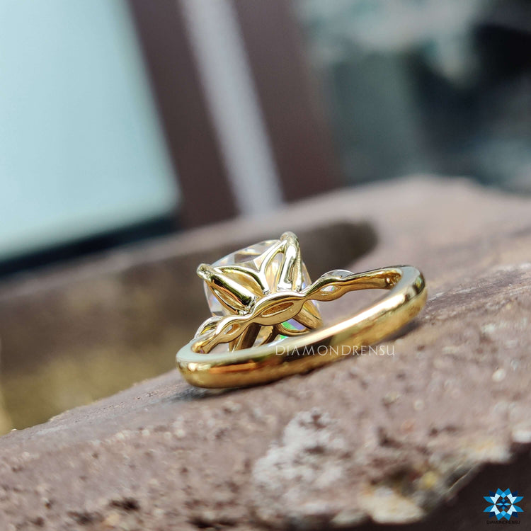 4 prong claw setting holding a cushion cut moissanite with two side stones.
