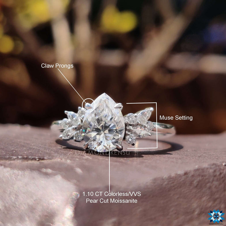 Prong setting ring with pear cut moissanite and side stones.
