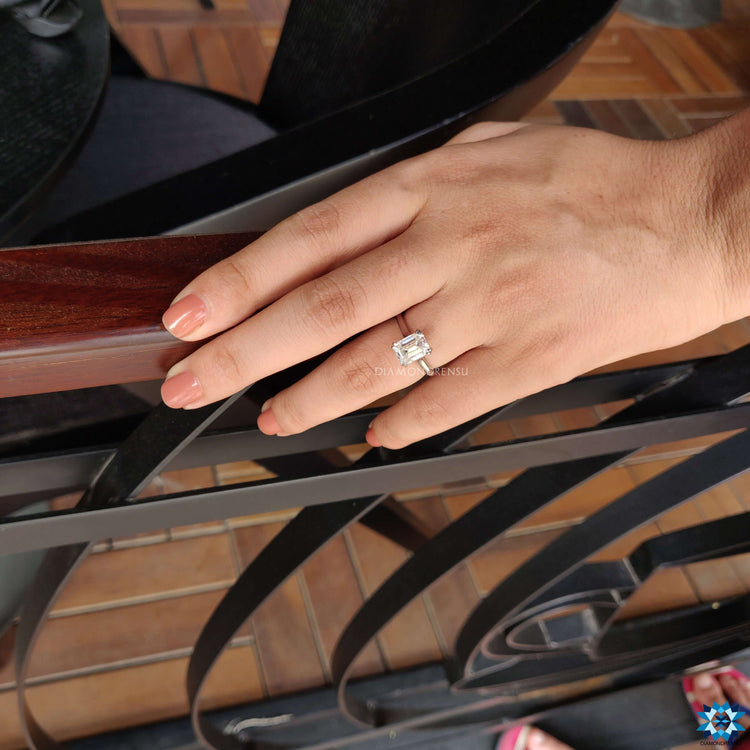 White gold ring with emerald cut center stone.
