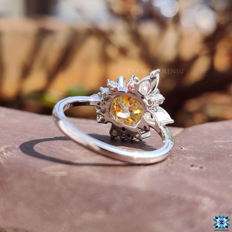 Muse-style engagement ring with cushion cut moissanite and mixed side stones.
