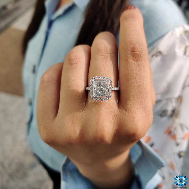 Halo engagement ring with radiant cut moissanite center stone.
