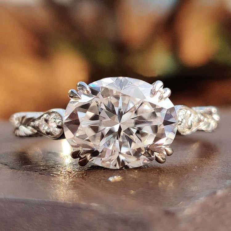 Oval moissanite engagement ring with vintage-inspired milgrain detailing.
