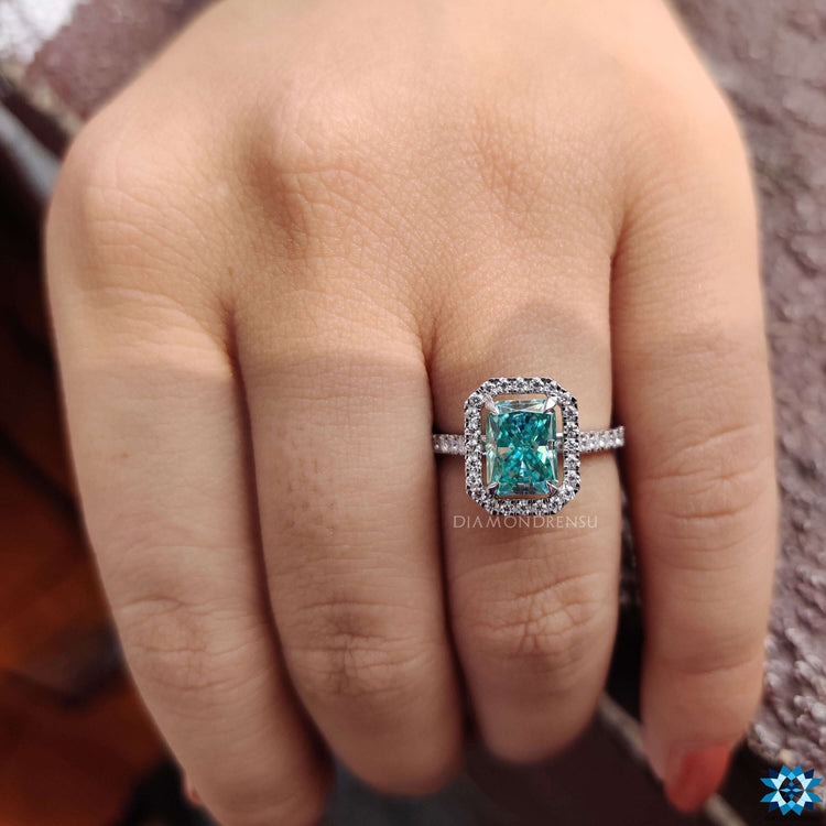 Blue moissanite halo ring in white gold with claw prong setting.
