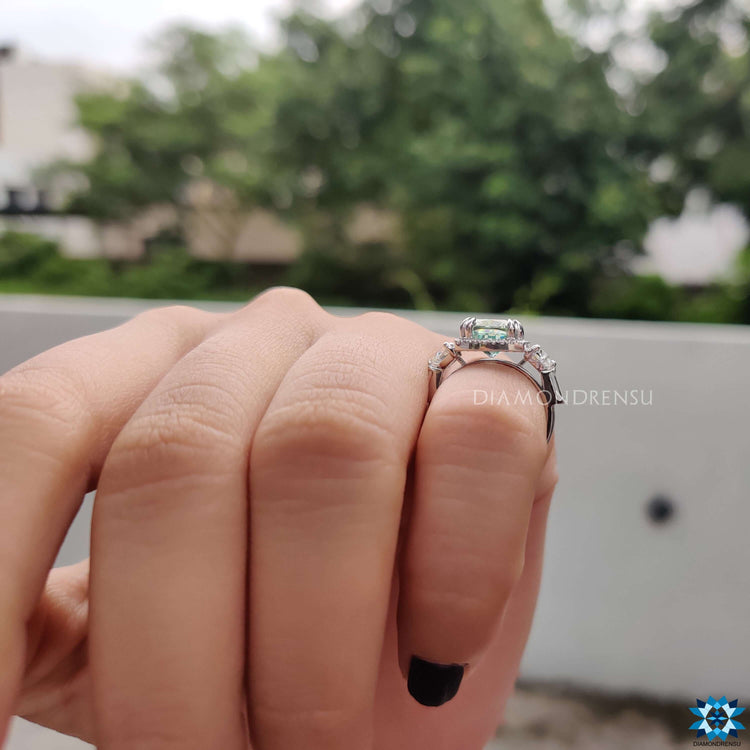 White gold engagement ring featuring cyan moissanite center.
