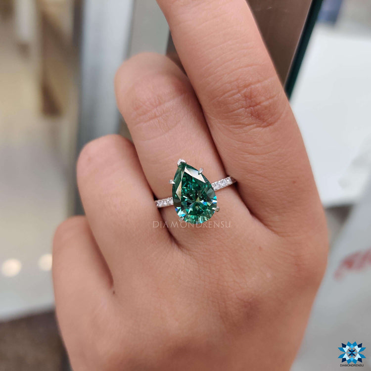 Green moissanite ring in white gold setting.
