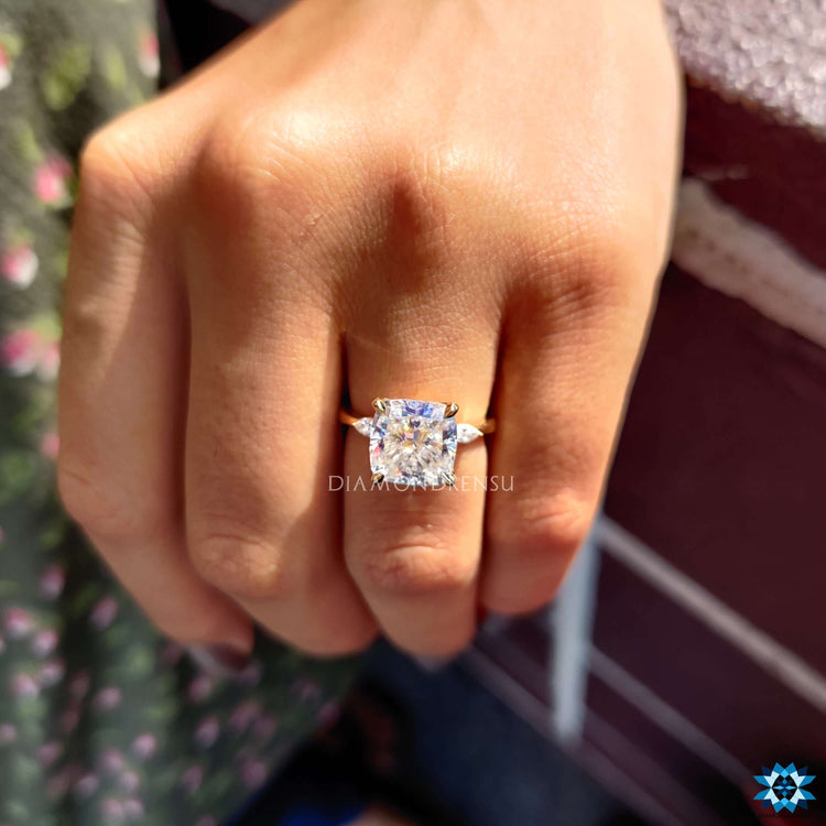 Cushion cut centre stone flanked by two pear side stones in a three stone moissanite ring.
