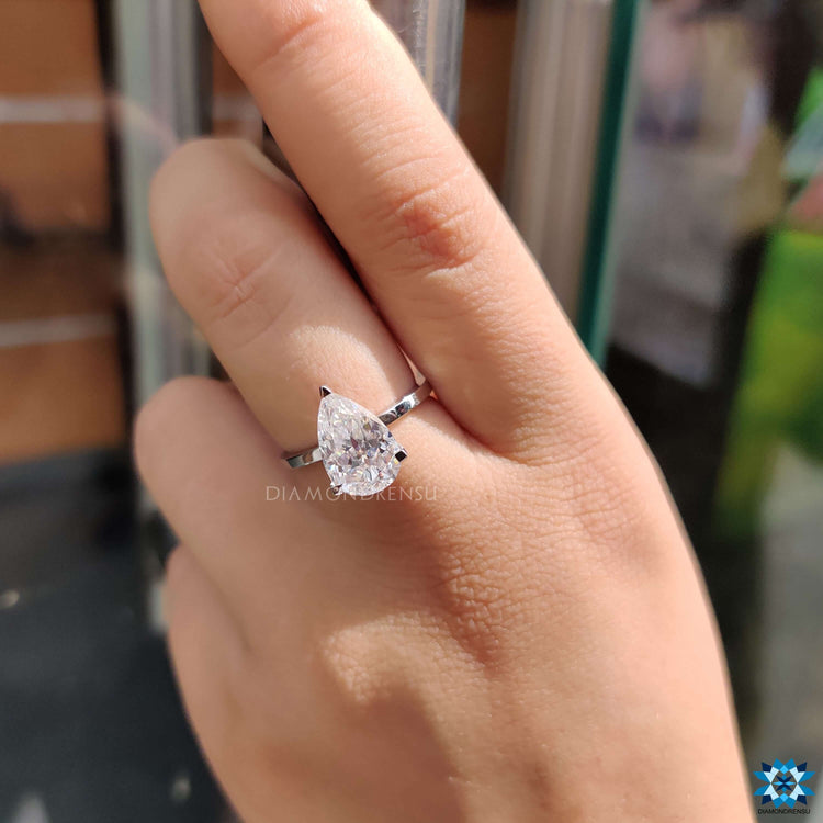 White gold engagement ring featuring a pear cut moissanite.
