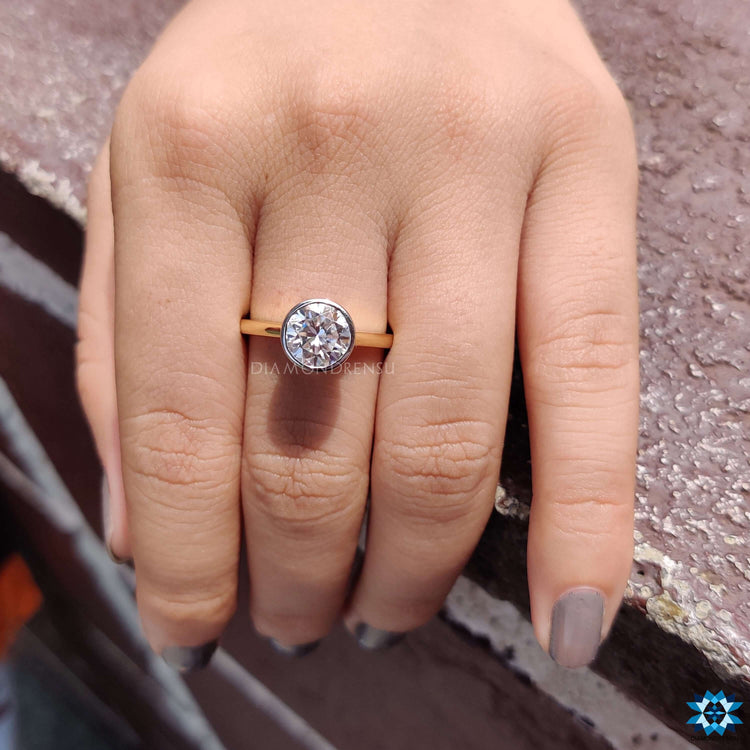 Yellow gold ring with round cut bezel set moissanite.
